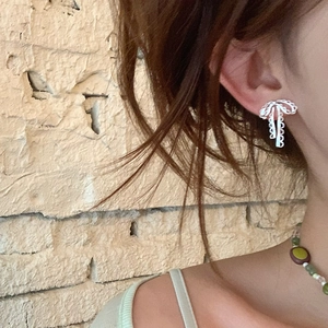 Vue détaillée des boucles d'oreilles nœud en dentelle argentée portées avec finesse