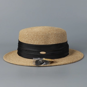 Détail du chapeau canotier en paille avec ruban plissé noir et plaque en métal doré
