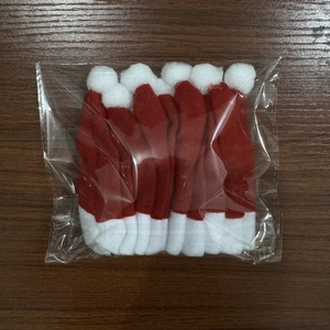 Set da 10 mini cappelli di Babbo Natale per posate su sfondo di legno scuro