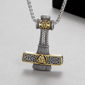 Macro shot of stainless steel Mjölnir pendant with golden Valknut and Celtic patterns