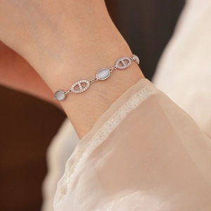 Gros plan d'un bracelet à maillons argenté avec œil de chat ovale et zircons blancs