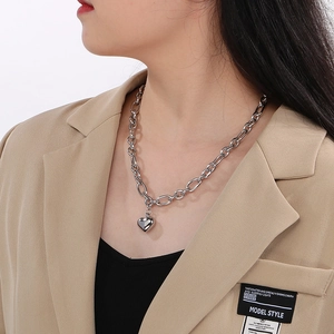Dettaglio di una collana con ciondolo a cuore in argento e catena a maglie ovali su modella