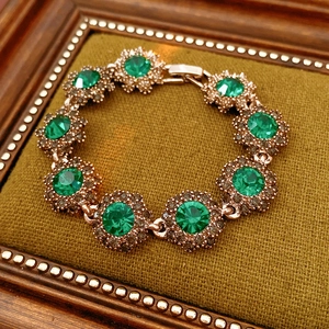 Close-up of vintage gold floral bracelet with green crystals in a velvet jewelry box