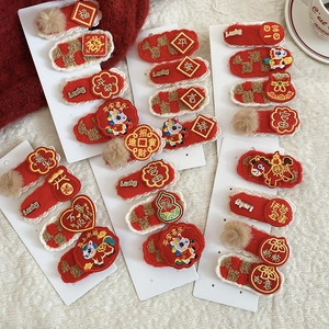 Detail showing red embroidered Chinese New Year hair clips with lucky characters on white card
