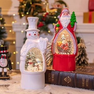 Santa and Snowman Christmas music boxes with glowing snow globes on vintage books