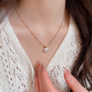 Detail of gold-plated necklace featuring shell star pendants on a dainty beaded chain