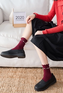 Detail of wine red knit socks featuring ruffled edges and delicate pearl embellishments
