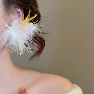 Close-up of white feather earrings with yellow and pink accents and gold bead details