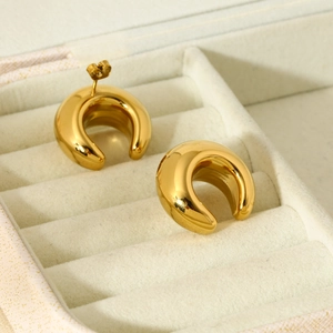 Macro shot of 16K gold plated C-shape earrings resting in a beige jewelry box tray
