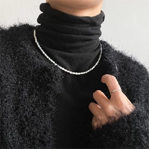 Elegant white shell bead necklace and minimalist silver ring worn on black knitwear