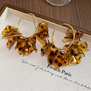 Detailed view of large gold hoop earrings featuring layered tortoiseshell resin petals