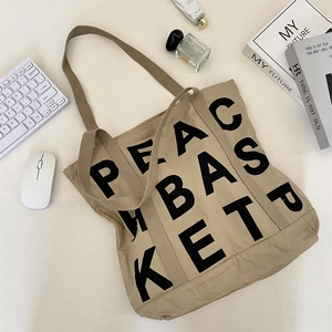 Detail shot of khaki canvas tote bag with PEACE BASKET print and office accessories