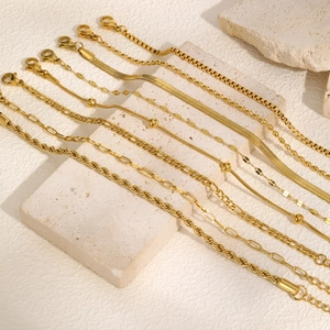 Set of eight assorted gold snake and twisted chain bracelets displayed on stone