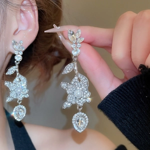 Dettaglio ravvicinato di orecchini a fiore scintillanti con perle e strass argentati