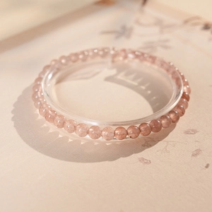 Detailed view of pink strawberry quartz beaded bracelet on a decorative ring holder