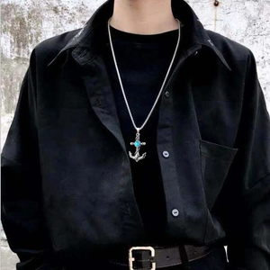 Silver anchor pendant necklace with blue gemstone worn by model on black shirt