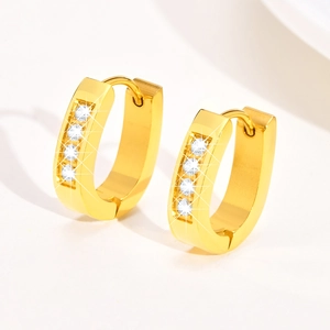 Close-up of golden U-shaped hoop earrings with four round white zircons on white background