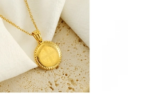 Detailed close-up of gold Saint Benedict Medal pendant on textured stone background