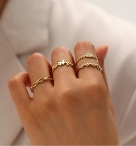 Detail of four thin gold butterfly rings with clear crystals worn on female fingers