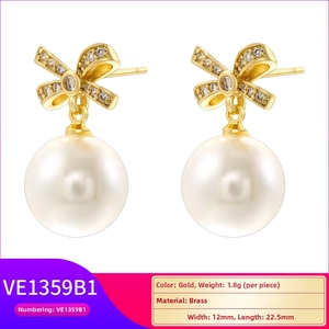 Detailed view of elegant gold bow earrings with dangling pearls and brass craftsmanship
