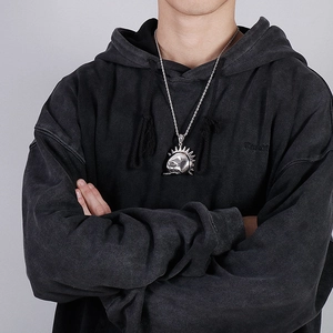 Detailed close-up of retro silver hip hop skull pendant with spiky sun gear on twisted chain
