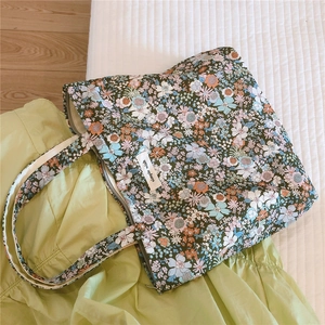 Détail d'un sac cabas en coton fleuri avec fermeture éclair et étiquette tissée