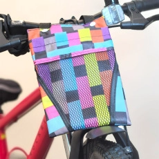Detail of colorful woven bicycle handlebar bag with black mesh pocket and buckle straps