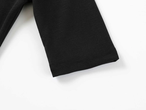 Macro detail of the high-quality double-stitched hem on this black knitted T-shirt sleeve