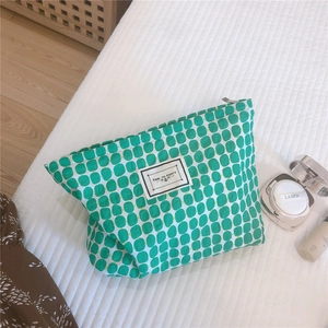 Detail of green geometric pattern makeup bag with Time to Party label on quilted fabric