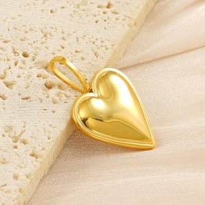 Macro shot of polished gold heart pendant resting on elegant silk and stone