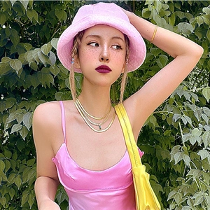 Pink terry cloth bucket hat paired with gold layering necklaces and a yellow handbag