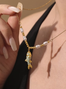 Detail of gold fish pendant with blue enamel scales and irregular pearls on thin chain