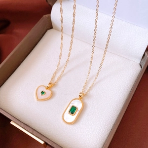 Detailed macro view of heart and oval gold pendants with emeralds in a jewelry box