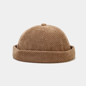 Close-up of brown knitted docker hat texture with rolled edge and top button detail