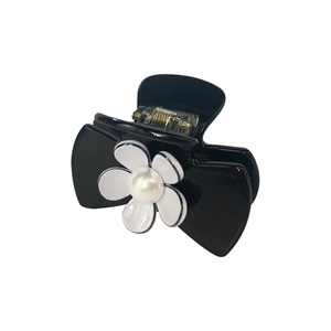 Detail of black shark hair claw featuring a white camellia flower with pearl center