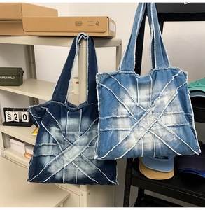 Detail of dark and light blue denim tote bags with unique cross-stitched frayed edge design