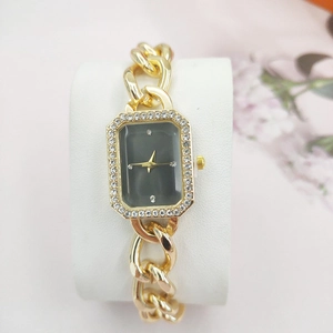 Close-up of golden rectangular watch with diamond-set bezel and black dial on display