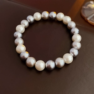 Detailed top-down view of a beaded bracelet with alternating white and grey pearls