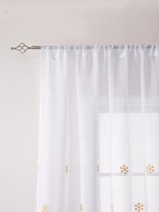 Close-up of white semi-transparent Christmas curtains with gold snowflake embroidery