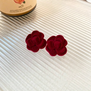 Close-up of vintage deep red flocked camellia flower earrings with luxury brand logo