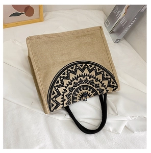 Close-up of khaki woven linen tote bag with black geometric pattern on a clean background