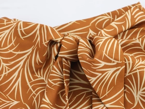 Detailed macro view of the knot design and white palm leaf print on brown fabric