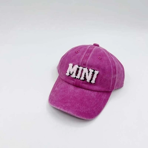 Close-up of white MINI towel embroidery on a washed dark pink baseball cap