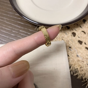 Detail of gold titanium steel dragon scale ring with irregular texture on a finger