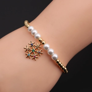 Détail du bracelet flocon de neige de Noël avec perles dorées et perles blanches