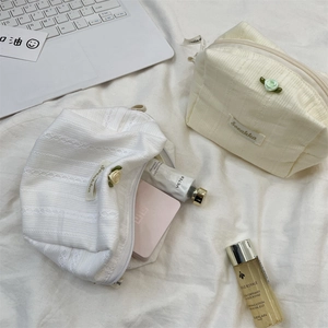 Detail of cream cosmetic bags with lace floral texture and ribbed fabric patterns