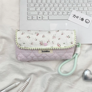 Detail of pink quilted floral pencil case with mint wrist strap and pompom trim