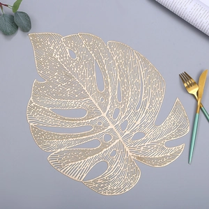 Detailed close-up of a golden PVC Monstera leaf placemat with hollow design and cutlery