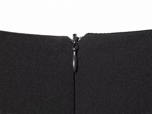 Close-up of a high-quality hidden zipper on a black pleated dress with fabric texture