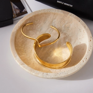 Vue détaillée de bracelets en acier plaqué or 18 carats sur un plateau en pierre